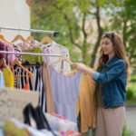 young woman shopping for dresses at garage sale